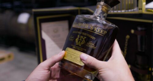 A person holding a bottle of the best single malt irish whiskey