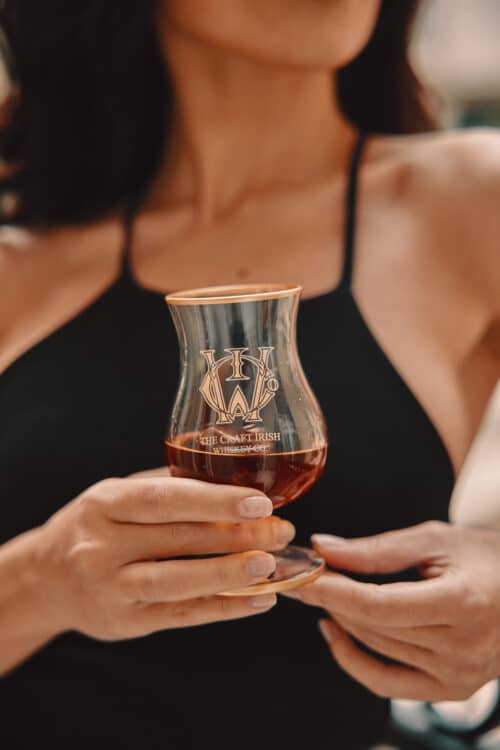 A woman holding a glass of an expensive whiskey brand