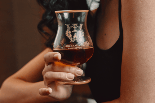 A woman holding a glass of handcrafted Irish whiskey