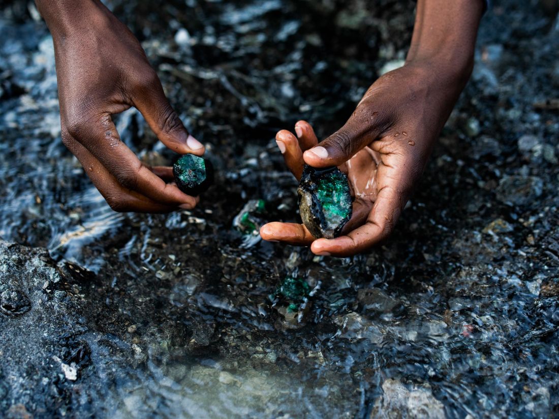 A man holding 2 emeralds, part of an expensive whiskey set