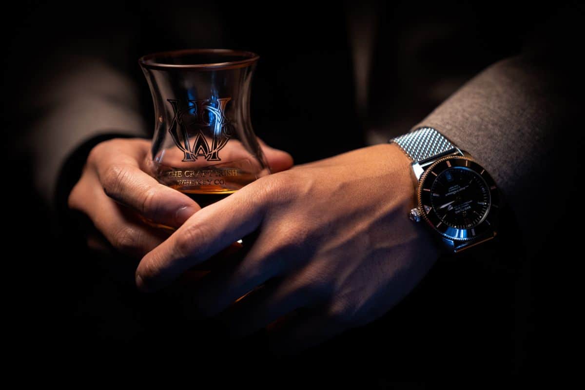 A man with a watch holding a glass of Irish whiskey