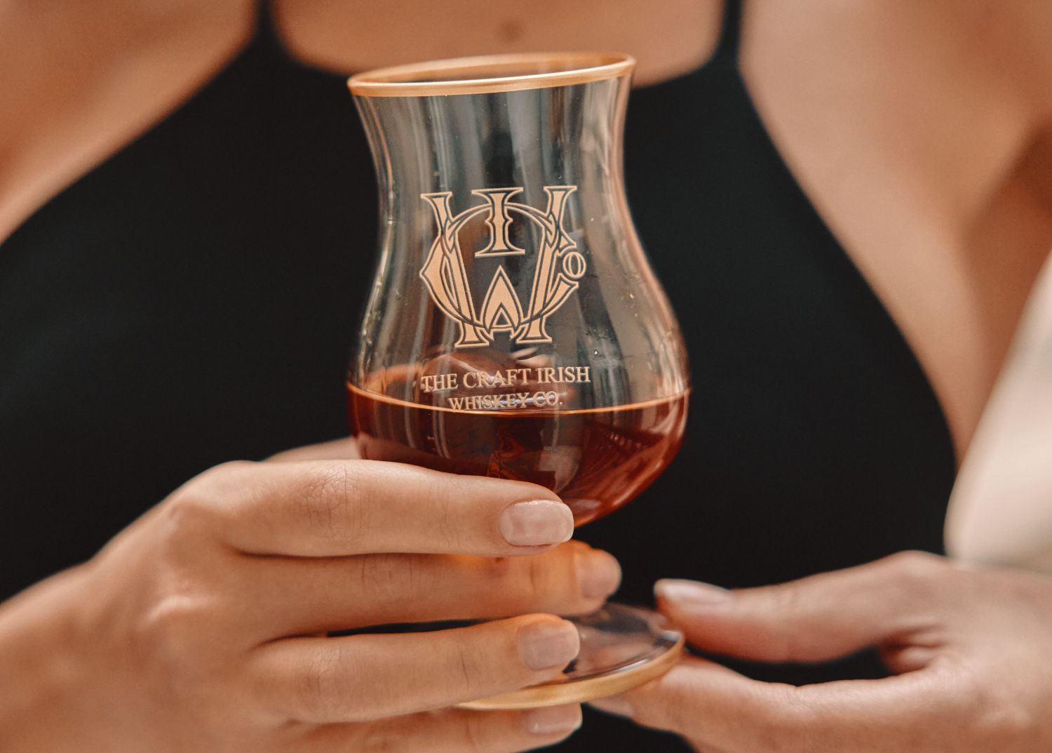 A woman holding a glass of an expensive whiskey brand