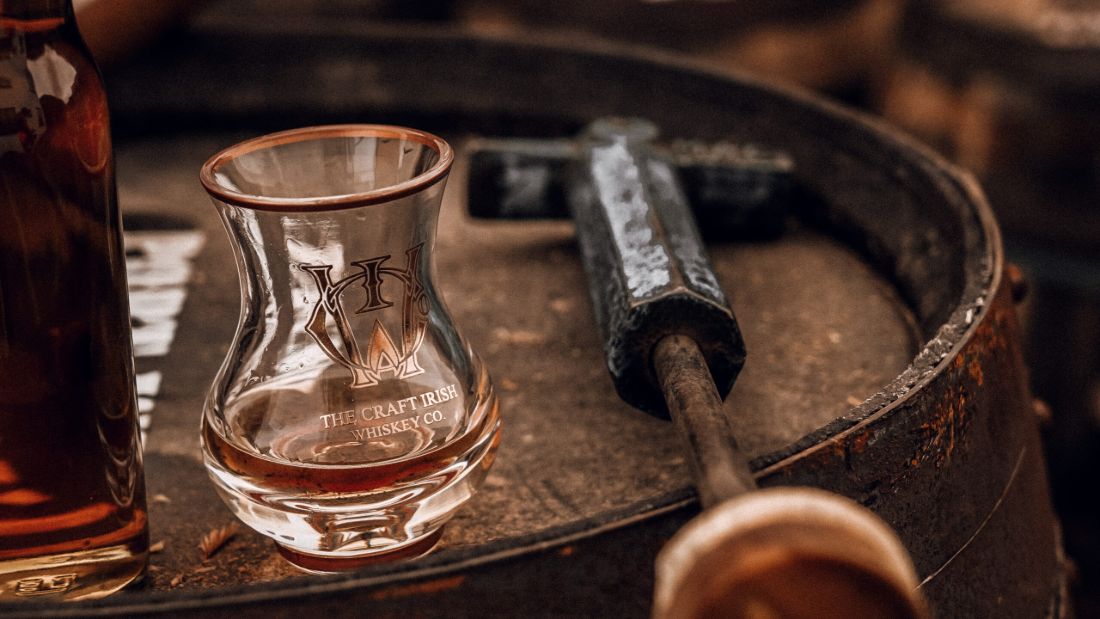 A glass of premium whiskey on a whiskey barrel