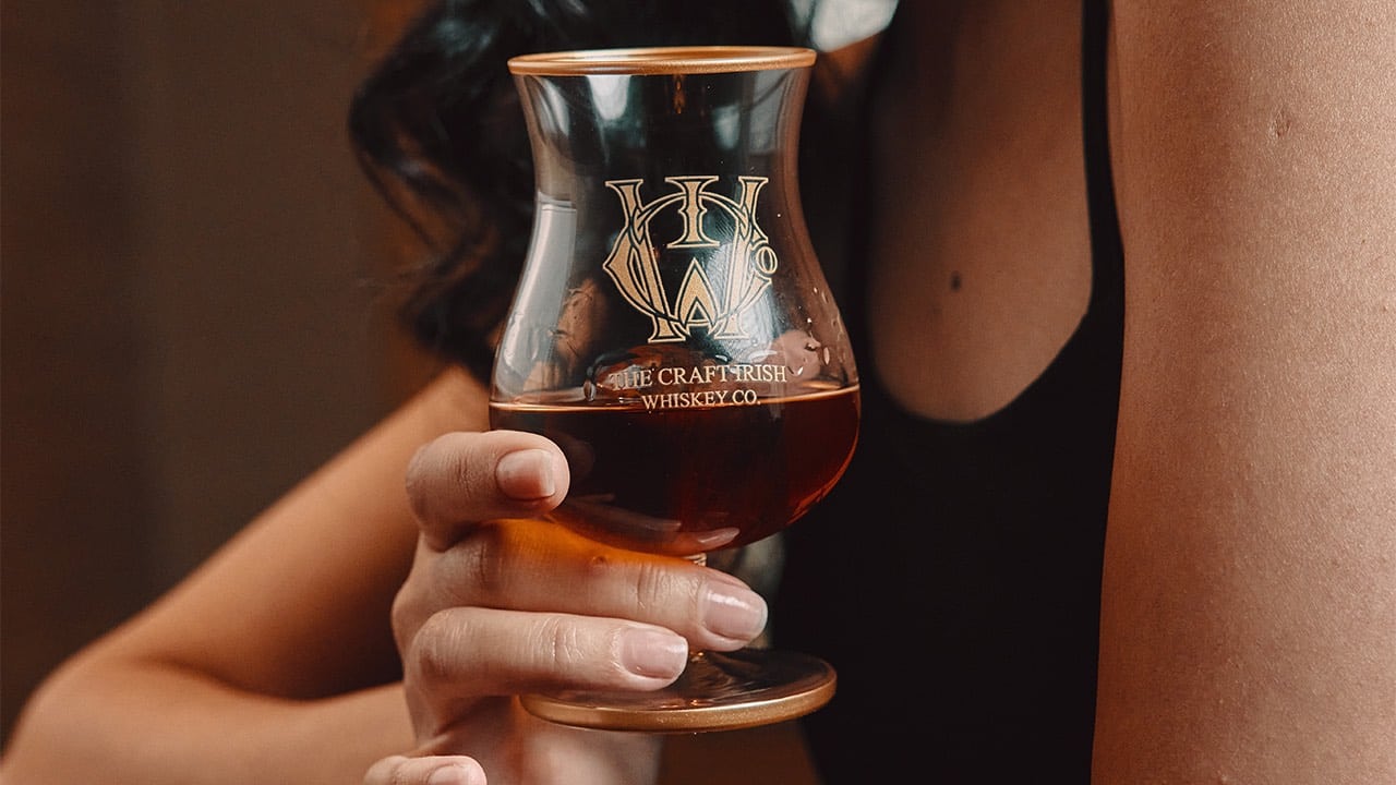 A woman holding a glass of rare whiskey