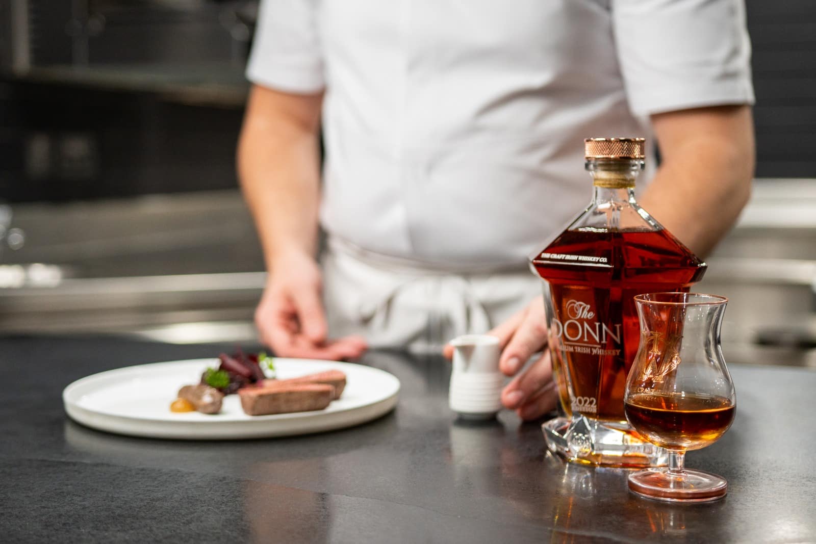 bottle of the Donn, luxury Irish whiskey, and a chef preparing a meal
